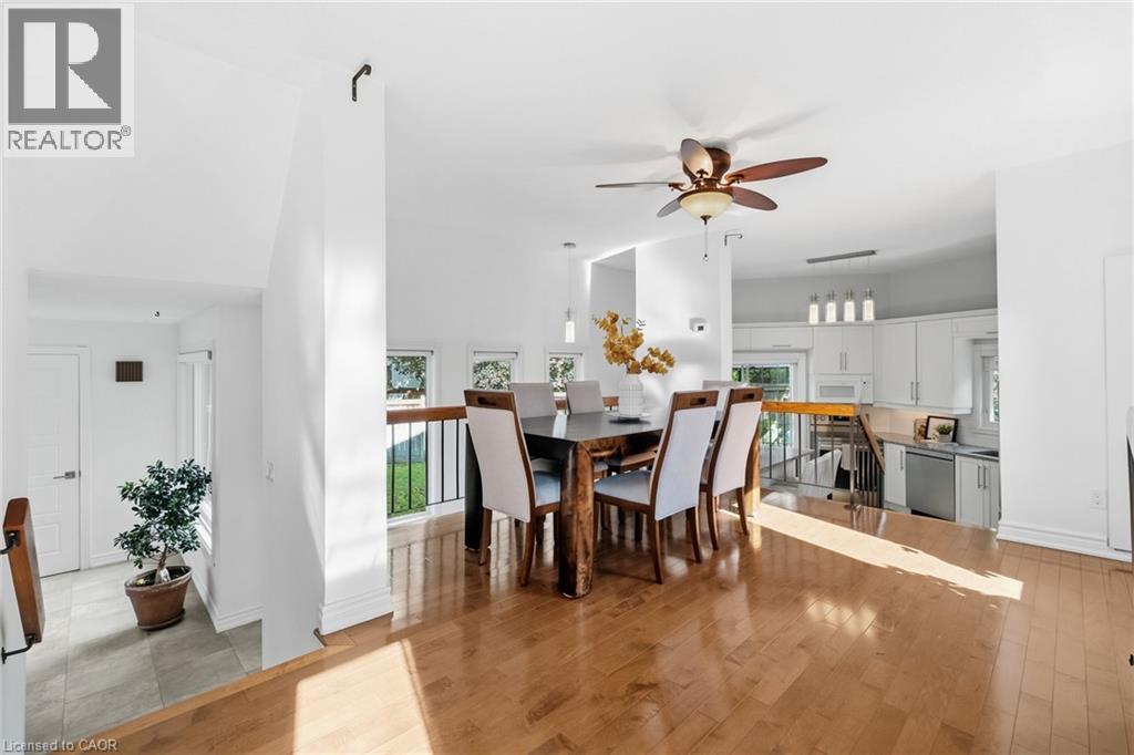 Open-concept dining area with wood-finish flooring, a ceiling fan, and abundant natural light
