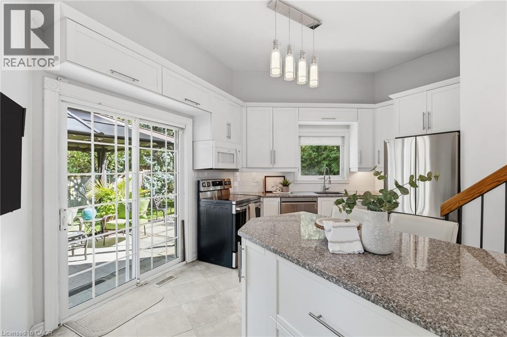 White shaker cabinetry, stainless steel appliances, granite countertops, tile flooring, and sliding glass patio doors