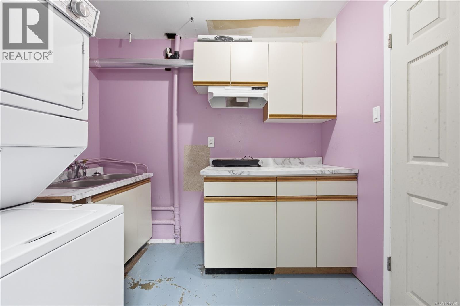 Built-in white cabinetry with wood-finish trim, a stainless steel sink, and light-toned countertops