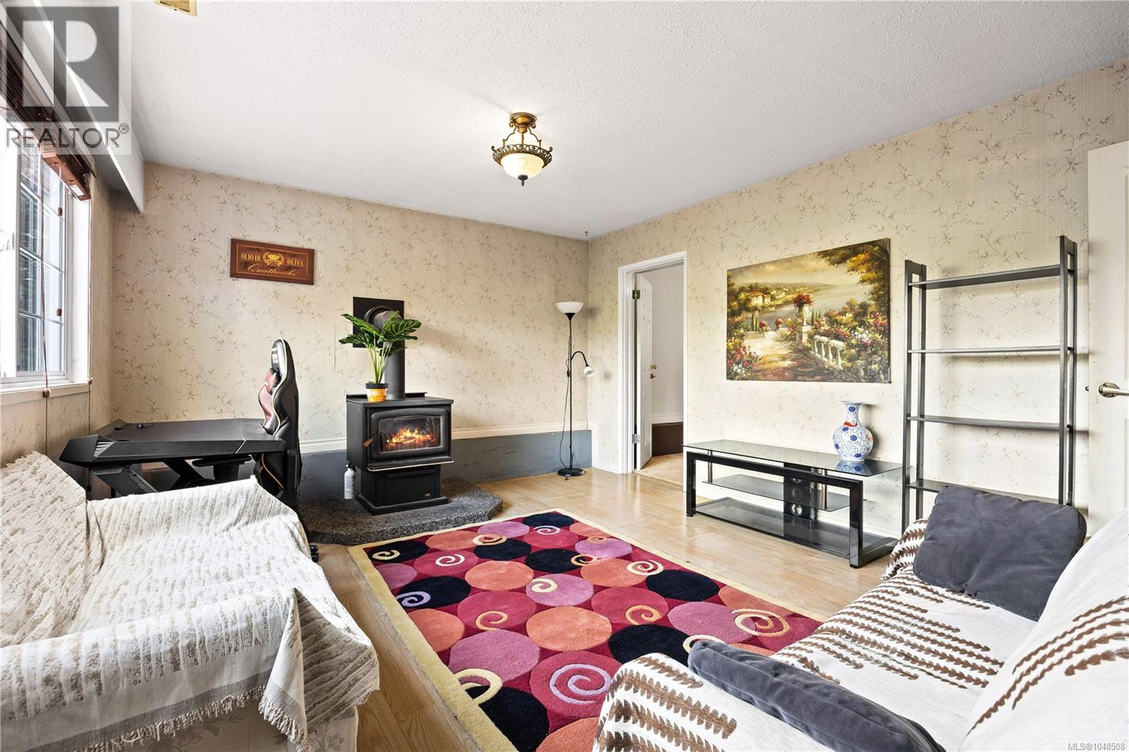 Wood-finish flooring, a functional wood-burning stove with a hearth, and an overhead light fixture
