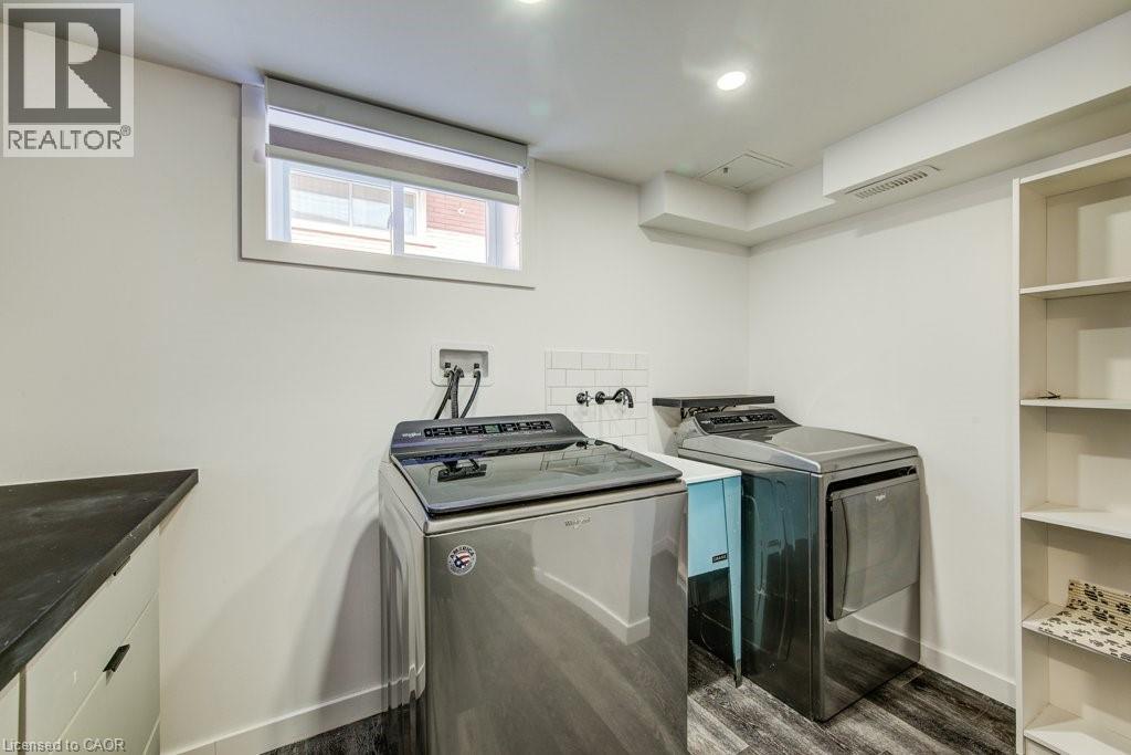 Dedicated laundry area featuring a utility sink, dark wood-finish flooring, and recessed lighting