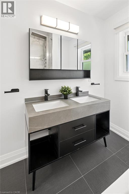 Dual-sink vanity with a light gray countertop, matte black faucets, and dark gray floor tiles