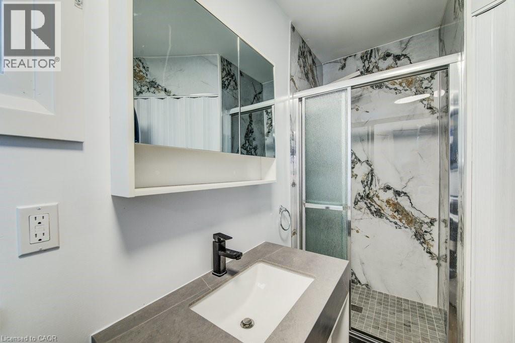 Modern bathroom featuring a walk-in shower with large format marble-look tile and a sliding glass door