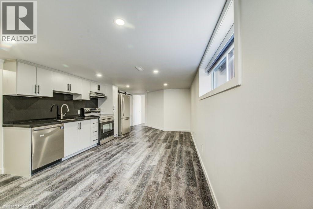 Contemporary kitchen featuring white cabinetry, dark countertops, a stainless steel appliance suite, and wood-finish flooring