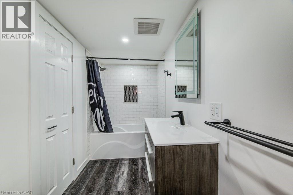 Contemporary bathroom featuring a white subway tile shower, built-in shower niche, dark wood-finish vanity with an integrated sink, and dark wood-finish flooring