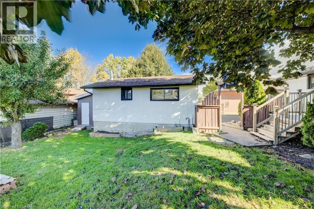 Expansive grassy backyard featuring a multi-level wood deck with railings, a wood privacy fence, and mature trees