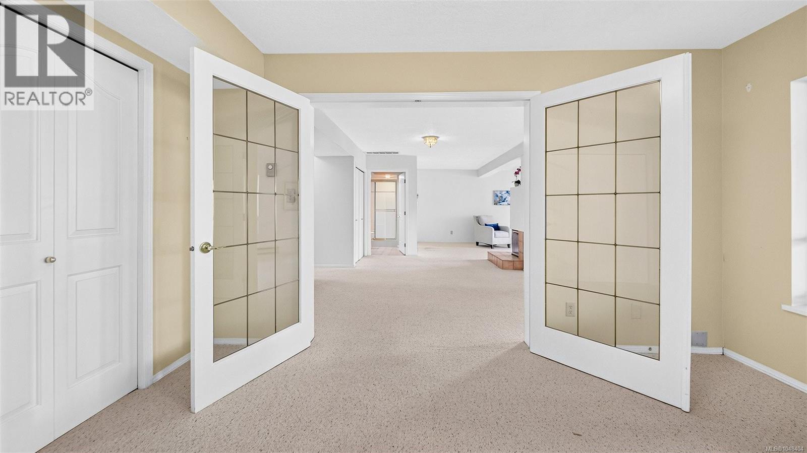 Lower level bedroom with double doors into the rec room. The lower bathroom is seen across the room.