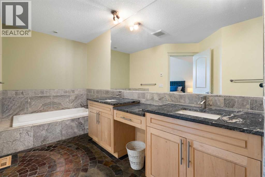 Primary bedroom 5-piece en-suite, soaker tub with stone tile surround, double sinks, vanity table, granite counter, stone tile backsplash